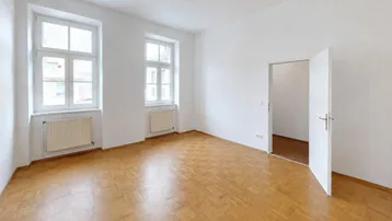 Helles Zimmer mit Parkettboden, weißen Wänden und zwei Fenstern, ideal als Wohn- oder Schlafzimmer.