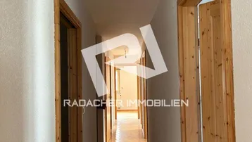Langer Flur mit Holztüren und hellem Holzfußboden, der zu weiteren Räumen führt.