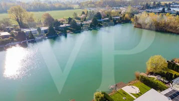 Luftaufnahme des Anwesens am See mit umliegender Natur und weiteren Häusern.