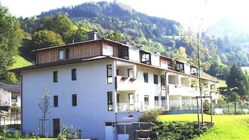 Mehrfamilienhaus in ländlicher Umgebung mit Bergblick und Balkonen.