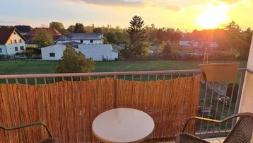 Gemütlicher Balkon mit Sitzgelegenheiten und weitem Blick über die ländliche Umgebung bei Sonnenuntergang.