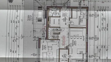 Grundriss des Erdgeschosses mit offenem Wohnbereich, Küche und Zugang zur Terrasse.