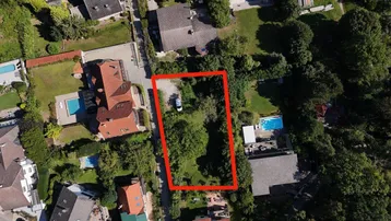 Luftaufnahme eines Wohngebiets mit einem rot umrandeten Grundstück und umliegenden Häusern mit Pools.