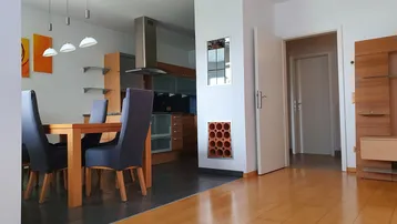 Heller offener Wohn- und Essbereich mit Holzboden, Esstisch und Blick in die moderne Küche.