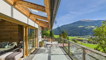 Geräumige Terrasse mit Glasdach, Holzbalken und atemberaubendem Bergblick, ideal für Entspannung im Freien.