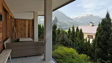 Geräumige Terrasse mit bequemen Outdoor-Möbeln und einem malerischen Bergblick.