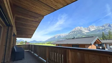 Geräumiger Holzbalkon mit Sitzgelegenheiten und atemberaubendem Blick auf die umliegende Berglandschaft.