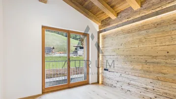 Schlafzimmer mit Holzbalkendecke, Holzwand und Zugang zu einem französischen Balkon.