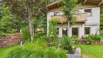 Garten mit Teich, üppiger Bepflanzung und Solarpaneelen zur Energiegewinnung.