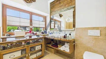 Geräumiges Badezimmer mit Doppelwaschbecken, WC und Fenster mit Bergblick.