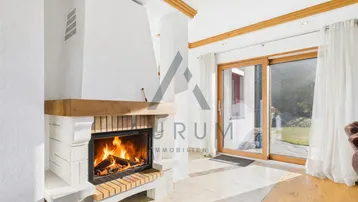 Gemütliches Wohnzimmer mit Kamin, Holzbalken und direktem Zugang zum grünen Garten.