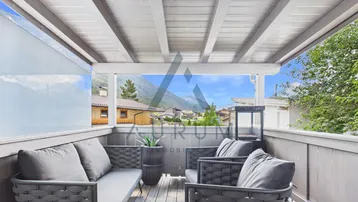Überdachter Balkon mit gemütlichen Sitzmöbeln und herrlichem Bergblick in alpiner Umgebung.