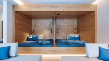 Gemütliche Holzkojen mit blauen Matratzen in einem Entspannungsbereich, ideal für Wellness.