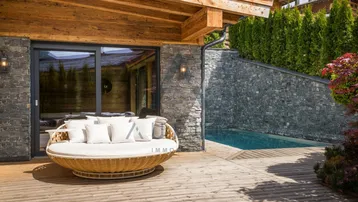 Gemütliche Terrasse mit bequemer Lounge und kleinem Pool, umgeben von Natursteinwänden und Holz.