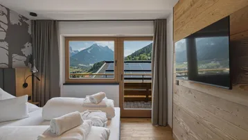 Gemütliches Schlafzimmer mit Holzelementen, Bergblick und Zugang zu einem Balkon.