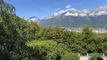 Weitläufiger Panoramablick auf majestätische Berge, üppige Bäume und eine Stadt in der Ferne.