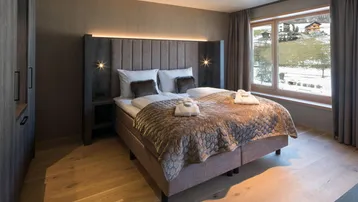 Komfortables Schlafzimmer mit Doppelbett, Holzboden und Blick auf die verschneite Landschaft.