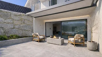 Moderne Terrasse mit gemütlicher Sitzgelegenheit, Feuerstelle und Blick auf die Umgebung.