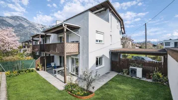 Modernes Reihenhaus mit gepflegtem Garten, Terrasse und Bergblick in sonniger Lage.