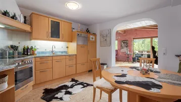 Funktionale Küche mit Holzeinbauten, Essbereich und offenem Zugang zum Wohnzimmer.