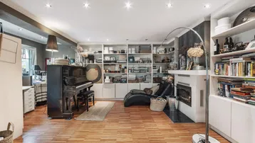Geräumiger Wohnbereich mit Klavier, Bücherregalen und Kamin.