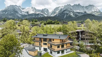 Modernes Mehrfamilienhaus in alpiner Umgebung mit beeindruckendem Bergblick und umliegender Natur.