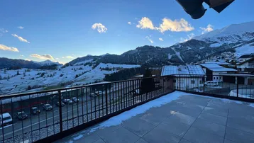 Große Terrasse mit Fliesenboden und weitem Blick auf die verschneite Berglandschaft.