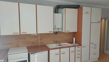 Helle Küche mit weißen Schränken, Holzoptik-Arbeitsplatten und Gastherme.