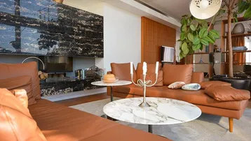 Gemütlicher Wohnbereich mit Ledersofas, Marmortischen und einem eleganten Kamin mit dunkler Verkleidung.