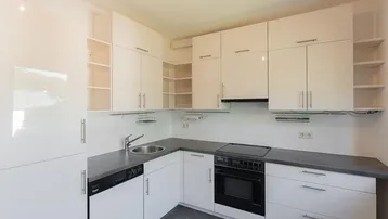 Moderne Einbauküche mit weißen Hochglanzschränken, Spüle und integrierten Geräten.