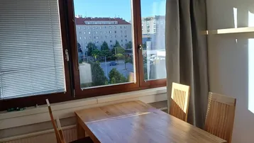 Heller Essbereich mit Holztisch und Stühlen, bietet einen Blick auf die Stadt durch große Fenster.
