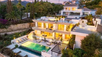 Luxuriöse moderne Villa bei Sonnenuntergang mit Infinity-Pool und weitläufigen Terrassenbereichen.