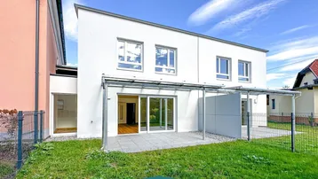 Moderne Doppelhaushälfte mit großer Terrasse und Garten, ideal für sonnige Tage im Freien.