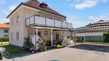Ansicht des Hauses von der Seite mit einem Balkon im Obergeschoss und einem Carport.