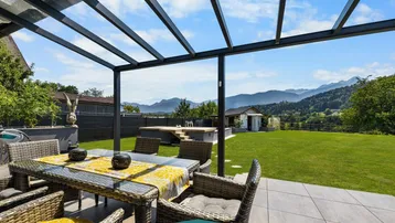 Überdachte Terrasse mit Esstisch und Stühlen, bietet einen herrlichen Bergblick.