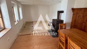 Geräumiger Wohn-Essbereich mit Holzboden, Kaminofen und rustikalem Esstisch.