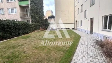 Grüner Gemeinschaftsgarten mit Rasenfläche und gepflegter Hecke zwischen den Wohngebäuden.