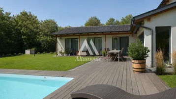 Große Holzterrasse mit Pool und Gartenmöbeln, umgeben von viel Grün und dem Haus.