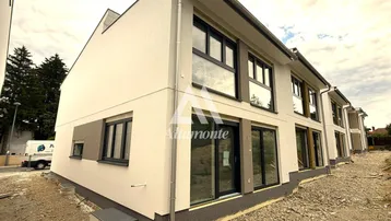 Moderne Neubaufassade mit großen Fenstern und noch unfertigem Außenbereich.