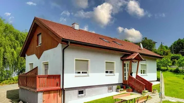 Freistehendes Einfamilienhaus mit Satteldach, Garten und kleiner Terrasse im Grünen.
