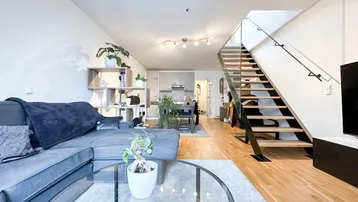 Geräumiger offener Wohn- und Essbereich mit moderner Treppe, Parkettboden und integrierter Küche.