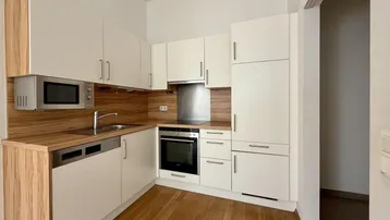 Moderne Einbauküche mit hellen Schränken, Holzarbeitsplatte und integrierten Geräten.