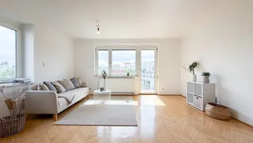 Helles Wohnzimmer mit Fischgrätparkett, großen Fenstern und Zugang zum Balkon.