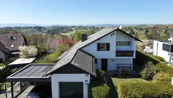 Haus mit Garage und Carport in ländlicher Umgebung mit Fernblick auf die Berge.