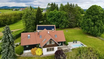 Luftaufnahme eines Landhauses mit Pool, Photovoltaikanlage und weitläufiger grüner Umgebung.