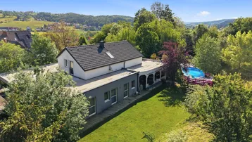 Luftaufnahme des Hauses mit großem Garten, Pool und umgebender grüner Landschaft.