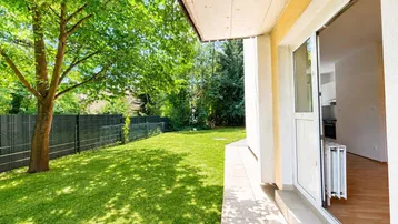 Gepflegter Gartenbereich mit Rasenfläche und direktem Zugang zu einer gefliesten Terrasse.