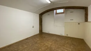 Geräumiger Kellerraum mit gewölbter Decke, kleinem Fenster und sichtbaren Ziegeln im Bogen.