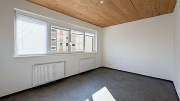 Lichtdurchfluteter Raum mit Holzbalkendecke und Blick auf die umliegenden Gebäude.