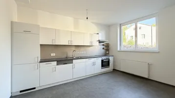 Moderne Einbauküche in Weiß mit grauer Arbeitsplatte und Fensterblick ins Grüne.